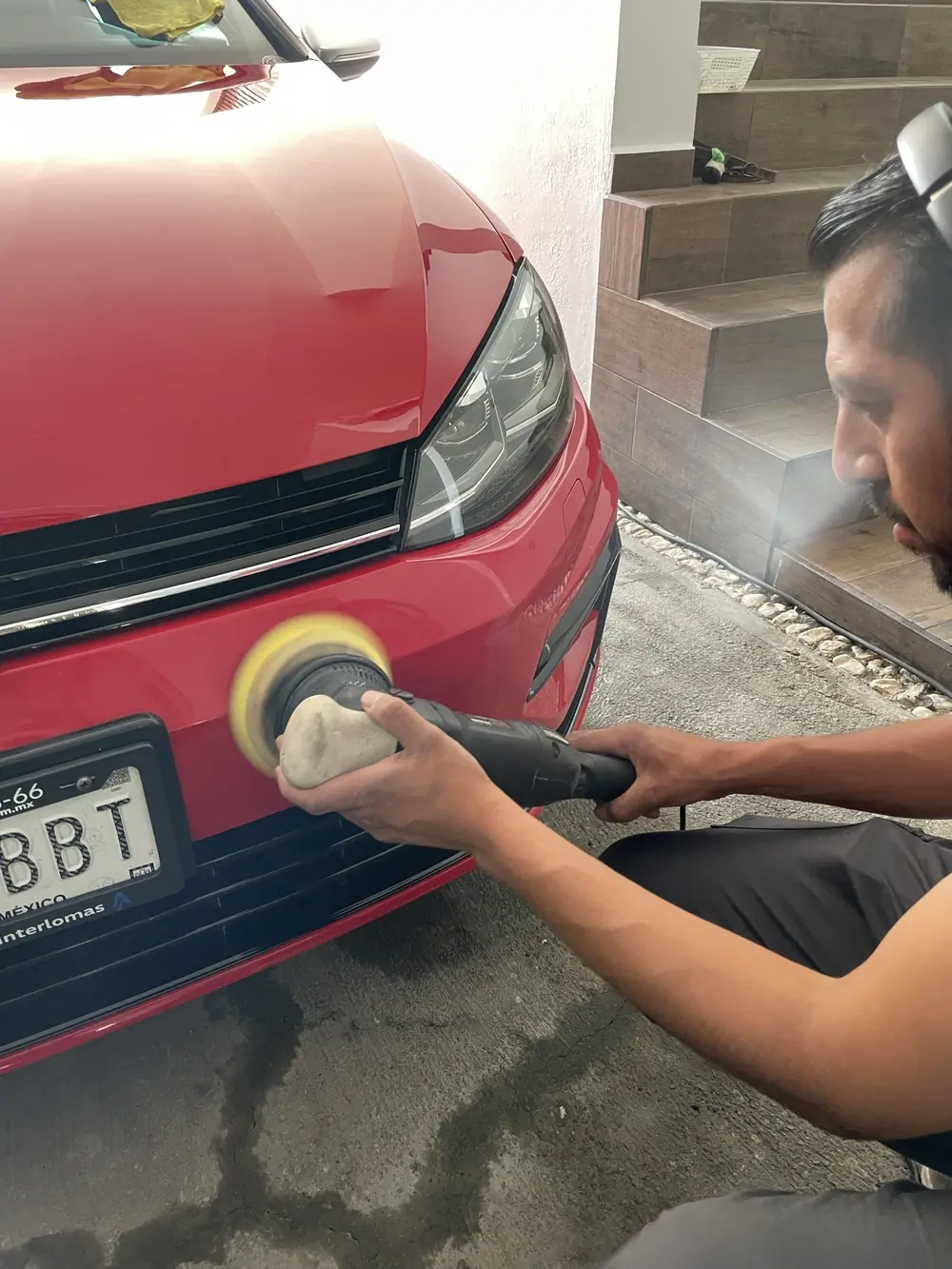 Detallador puliendo la cajuela de un Golf rojo